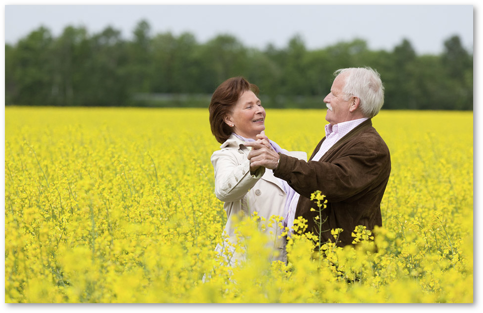 Mature couple dancing in field on a date